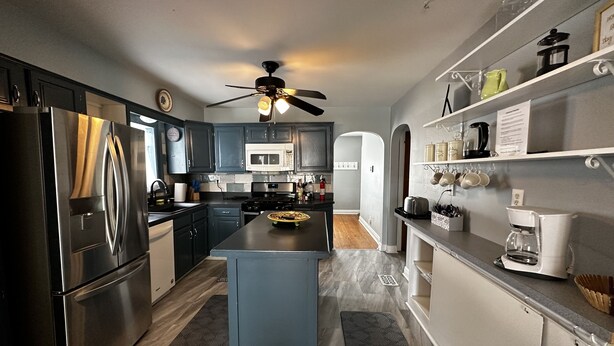 Una cocina moderna con gabinetes azul oscuro, electrodomésticos de acero inoxidable y una isla central.