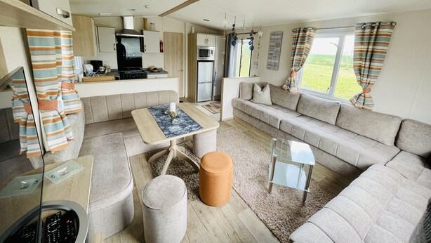 Een kleine woonruimte met een kitchenette, een bank, een salontafel en een televisie.
