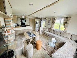 A compact living space with a kitchenette, a sofa, a coffee table, and a TV. - Cozy mobile home in a very quiet rural location (Neuenpleen)