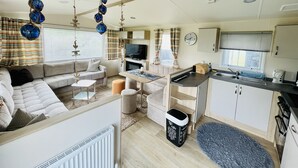 Een compact camperinterieur met een zithoek, kitchenette en eethoek.
