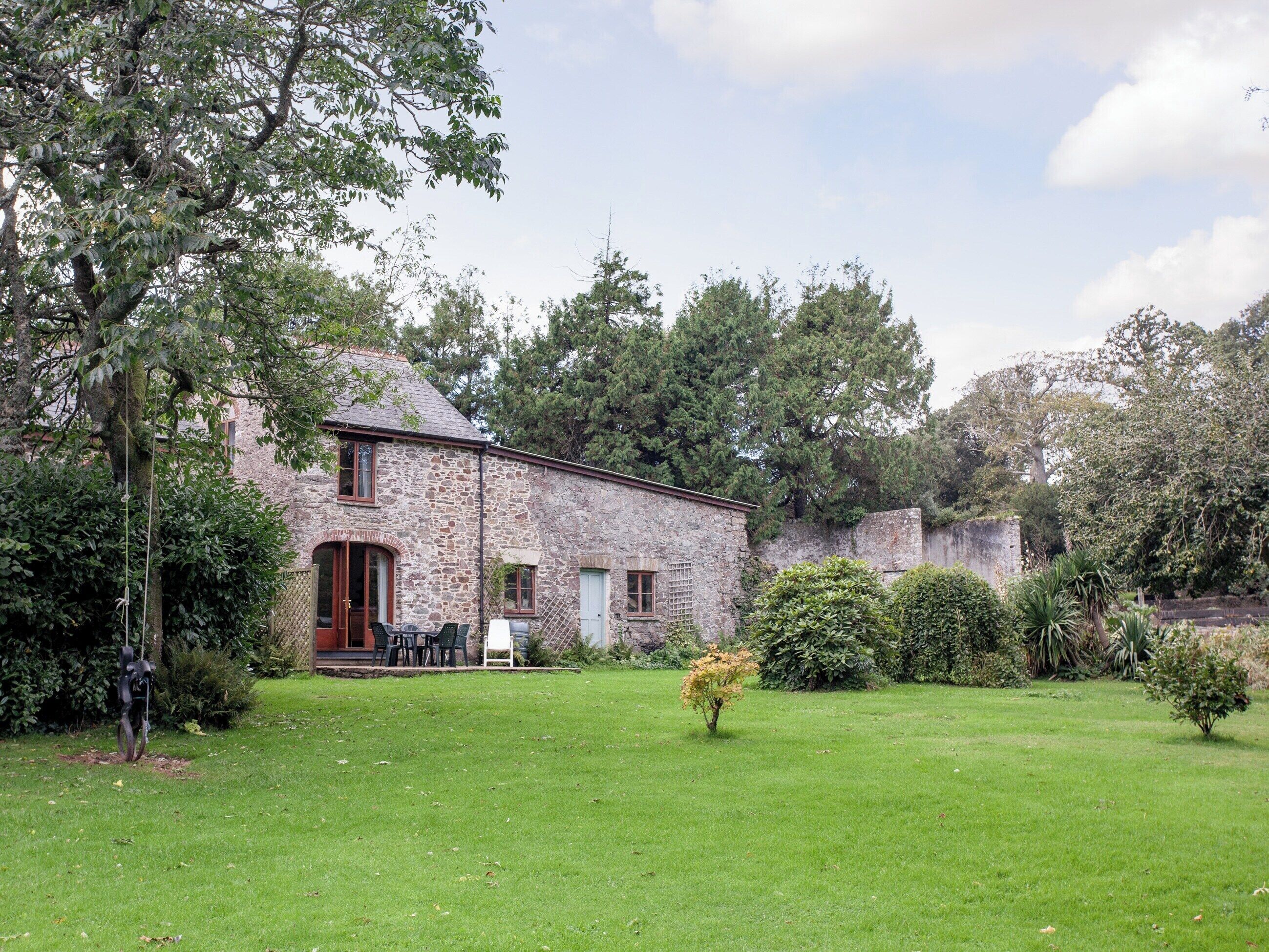 A stone building with a grassy yard and trees.