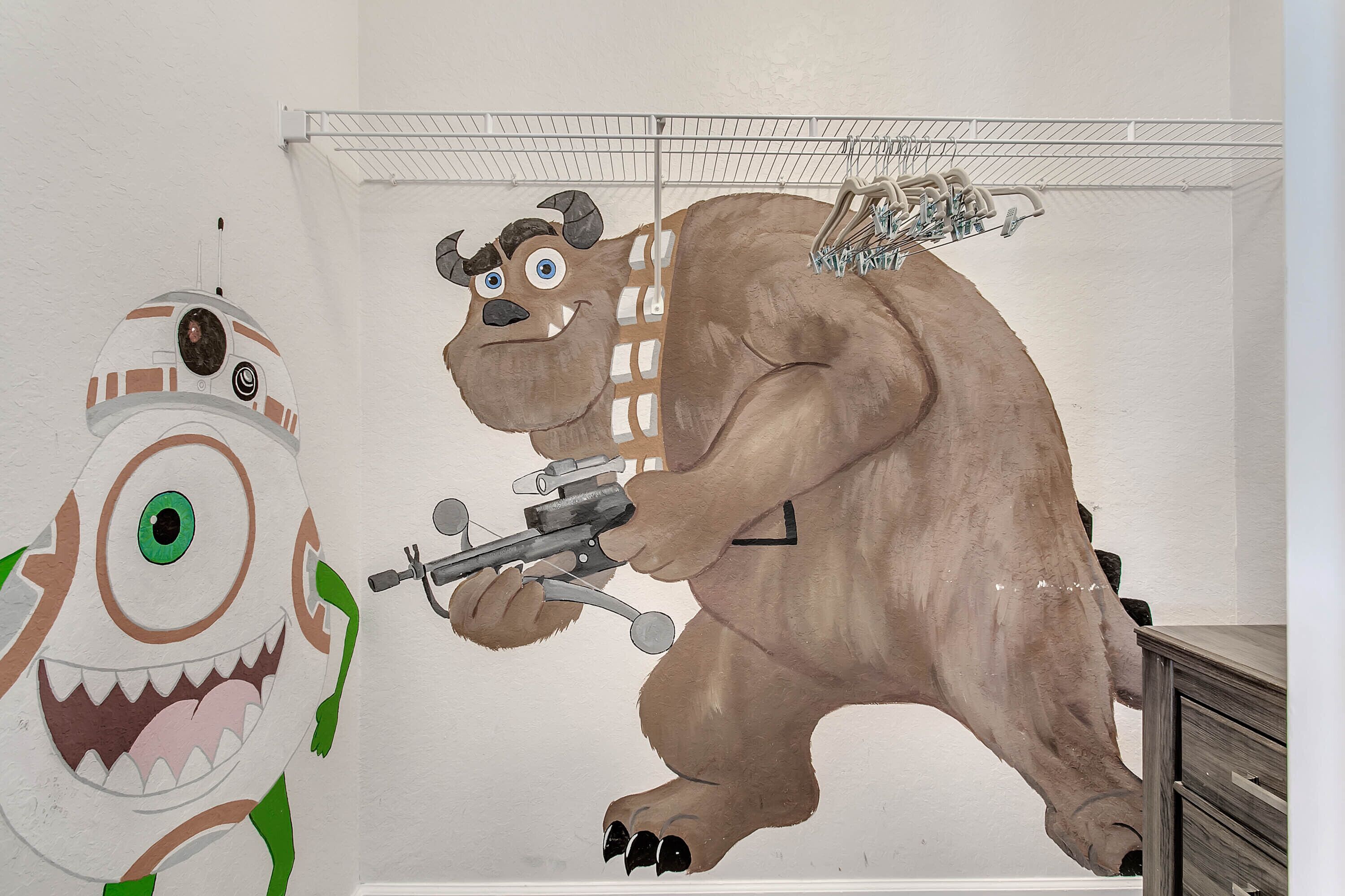 A room with a large wall mural of a cartoon character holding a gun, a metal shelf with hanging items, and a wooden dresser.