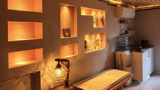 Una sala de spa amb bancs de fusta, prestatges penjats a la paret i un dispensador d'aigua.