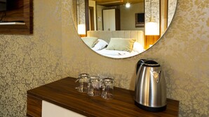 Una habitació d'hotel amb escriptori de fusta, mirall, llit i aire condicionat fixat a la paret.