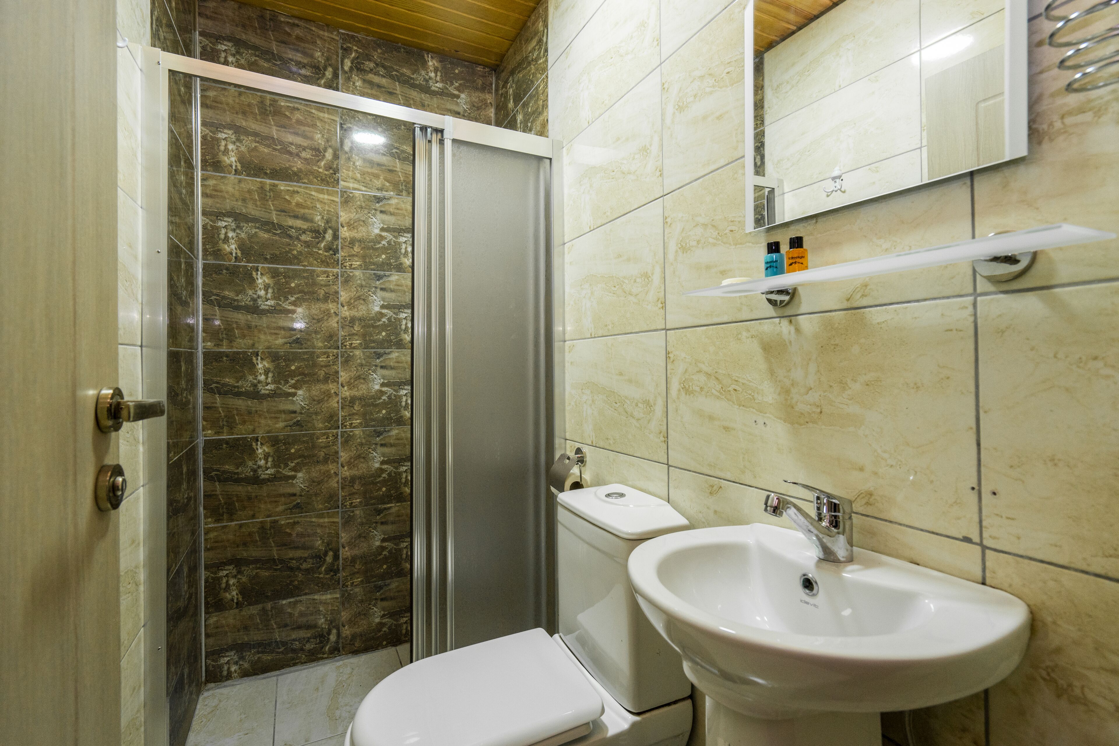Une salle de bain équipée d’une douche, de toilettes, d’un lavabo et d’un miroir au-dessus du lavabo.