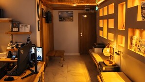 Rebedor d'hotel amb sostres de fusta panelada, una taquilla, un espai informàtic i una zona de seients amb taules.