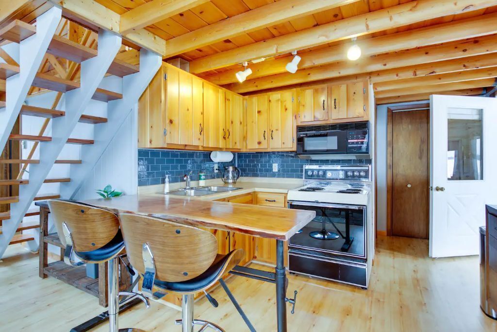 A modern kitchen with wooden cabinets, a central island, and a built-in oven.