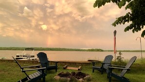 Un cadre idyllique au bord du lac, avec deux fauteuils Adirondack, une jetée et un bateau.