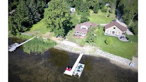 Vue aérienne d’une propriété au bord du lac, avec une maison, un quai et un bateau.