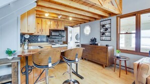 Une cuisine moderne avec des poutres en bois, un coin bar avec des tabourets et une table à manger.