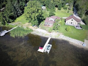 Vista aérea de una propiedad junto al lago, con una casa, muelle y barco.