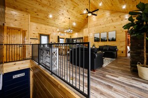A wooden cabin interior with a living area, a playroom, and a stone fireplace.