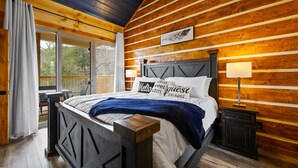 Quarto de cabana de madeira com cama, mesa de cabeceira, janela e vista para o exterior.
