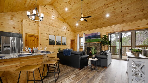 Interior espaçoso de uma cabana de madeira, com cozinha, sala de jantar e sala de estar.