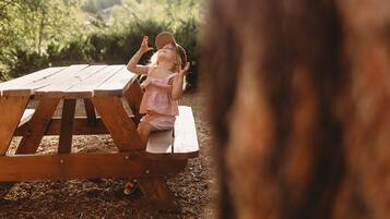 Een picknicktafel in een bebost gebied, met een kind dat erop zit.
