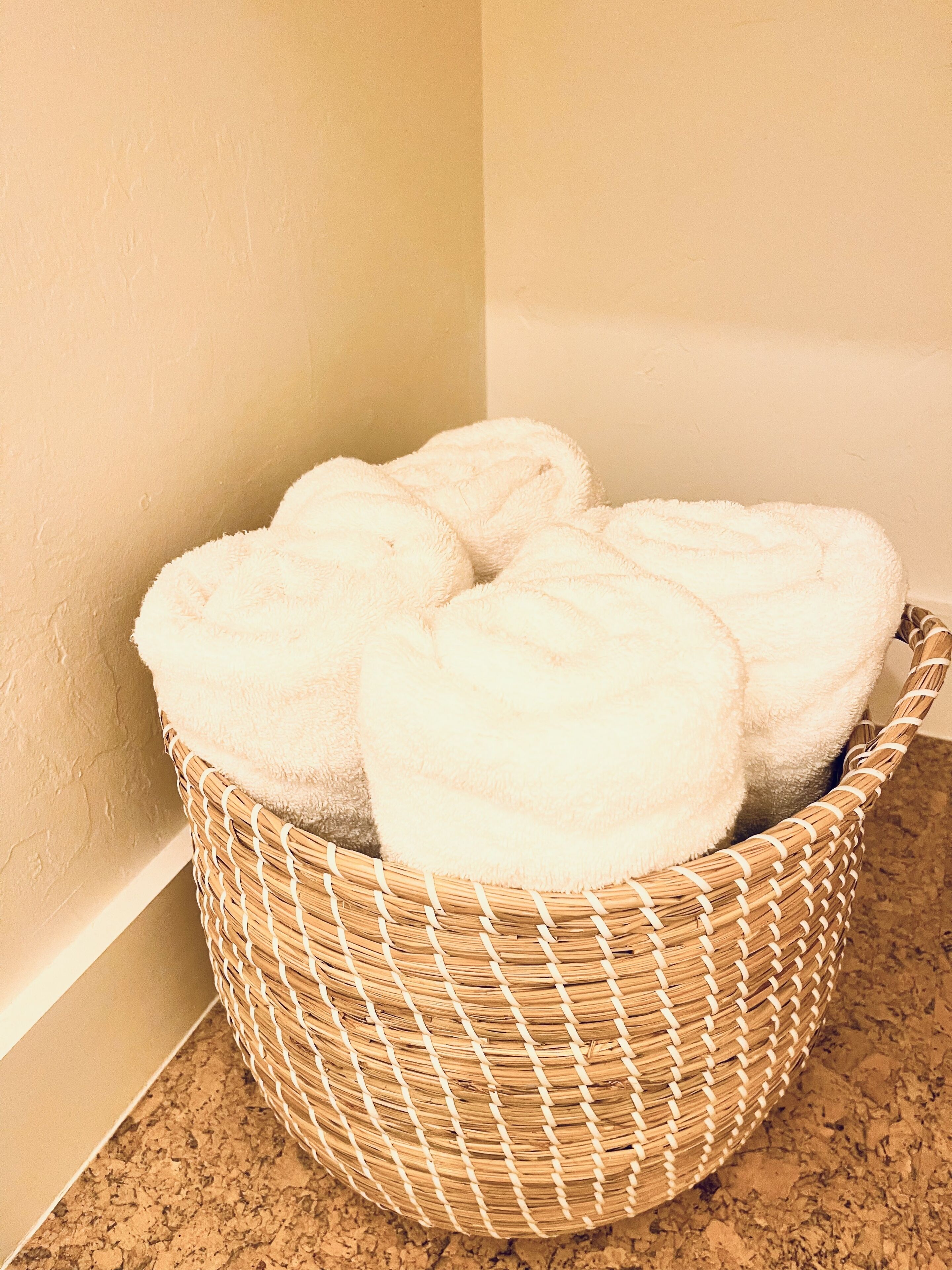 A wicker basket containing several white towels on a kitchen counter.