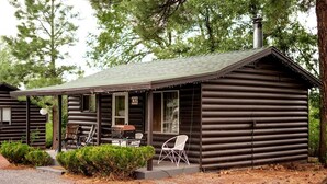 A log cabin with a porch, two chairs, a grill, and a number '02' sign. - Corduroy Boutique Lodge (Pinetop)