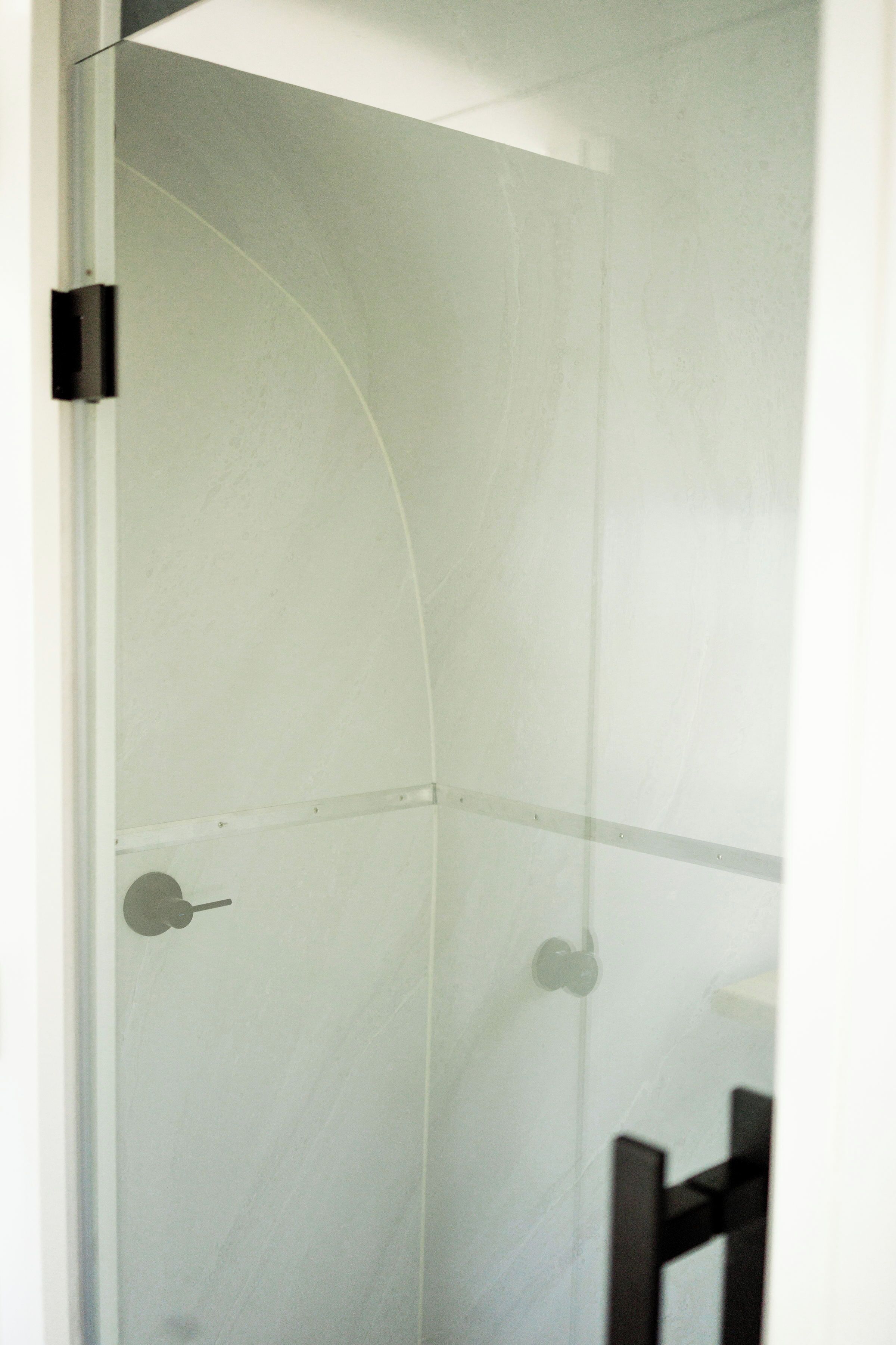 A bathroom with a curved shower enclosure and a visible towel rack.
