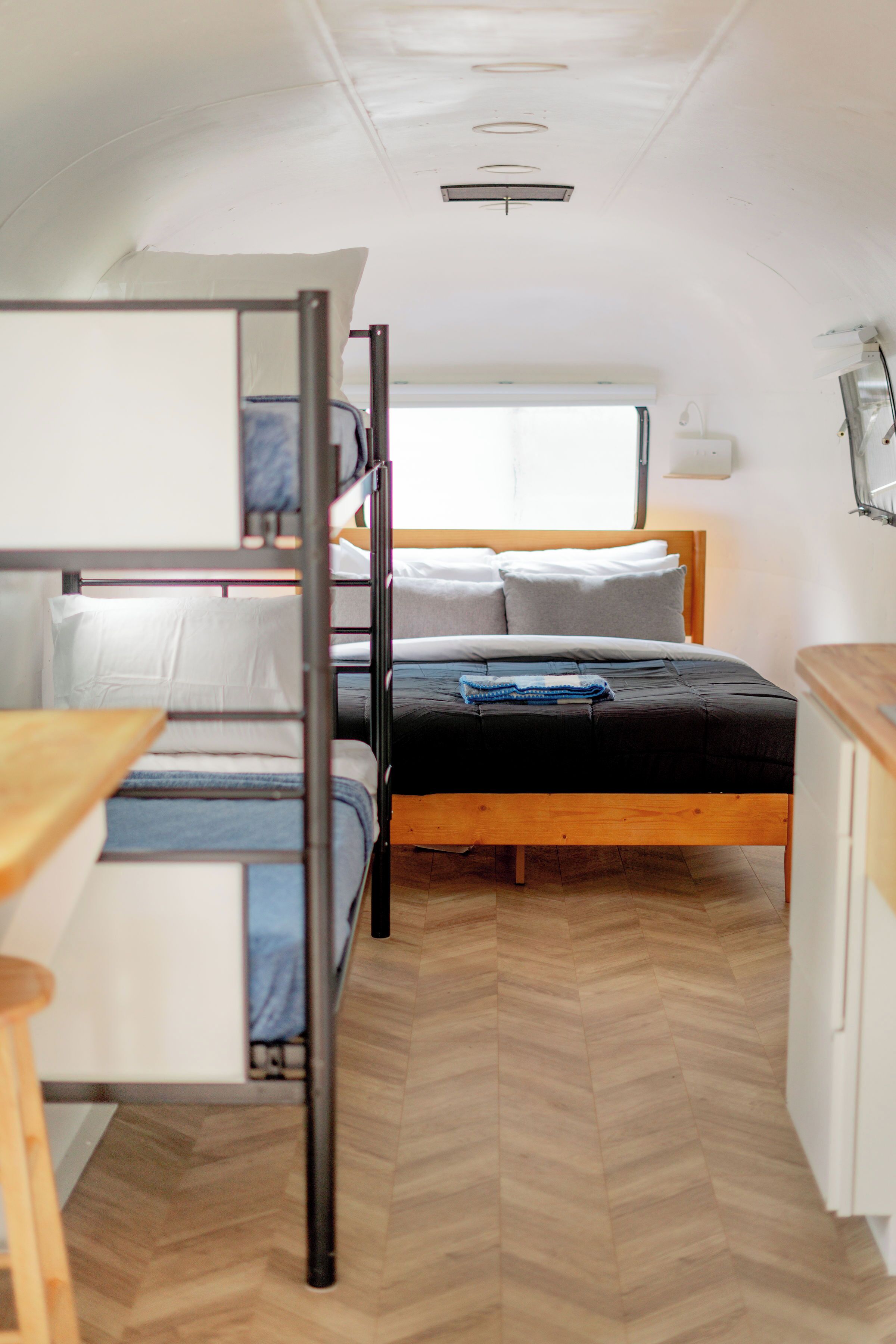 A compact, well-lit room with bunk beds, a small kitchenette, and a window providing natural light.