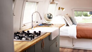 A compact kitchen with a gas stove, a sink, and a fan. - Corduroy Boutique Lodge (Pinetop)