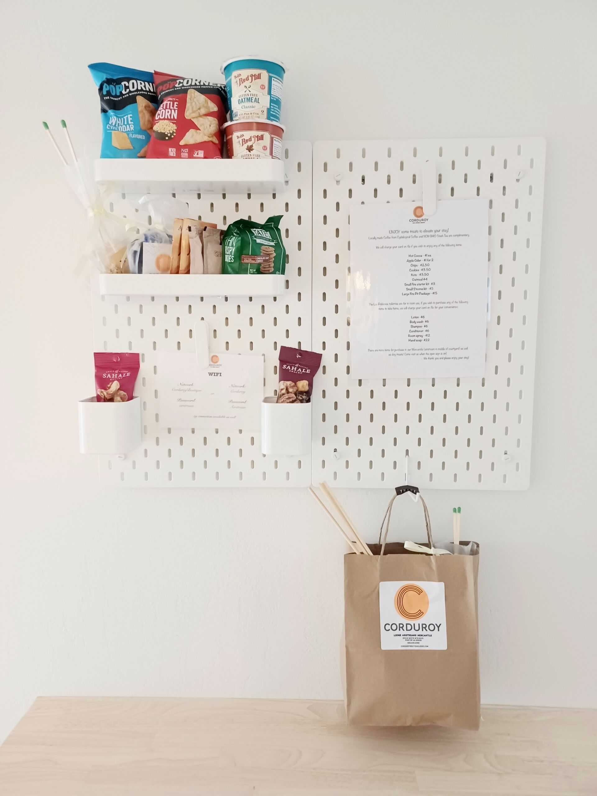 A wall-mounted pegboard with various food items and a Corduroy branded bag.