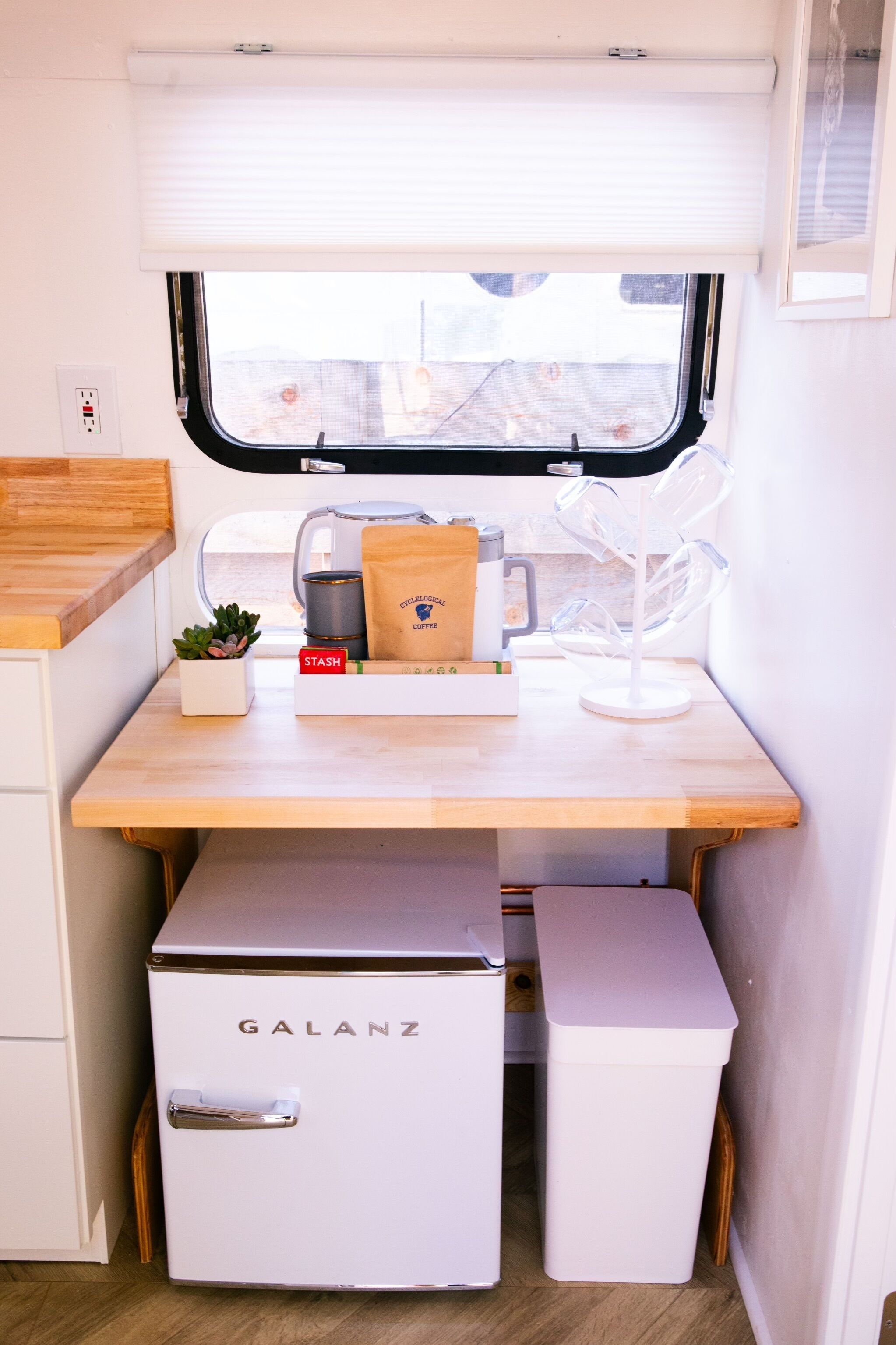 Una kitchenette compacta con un refrigerador Galanz, una cafetera y una pequeña planta en maceta.