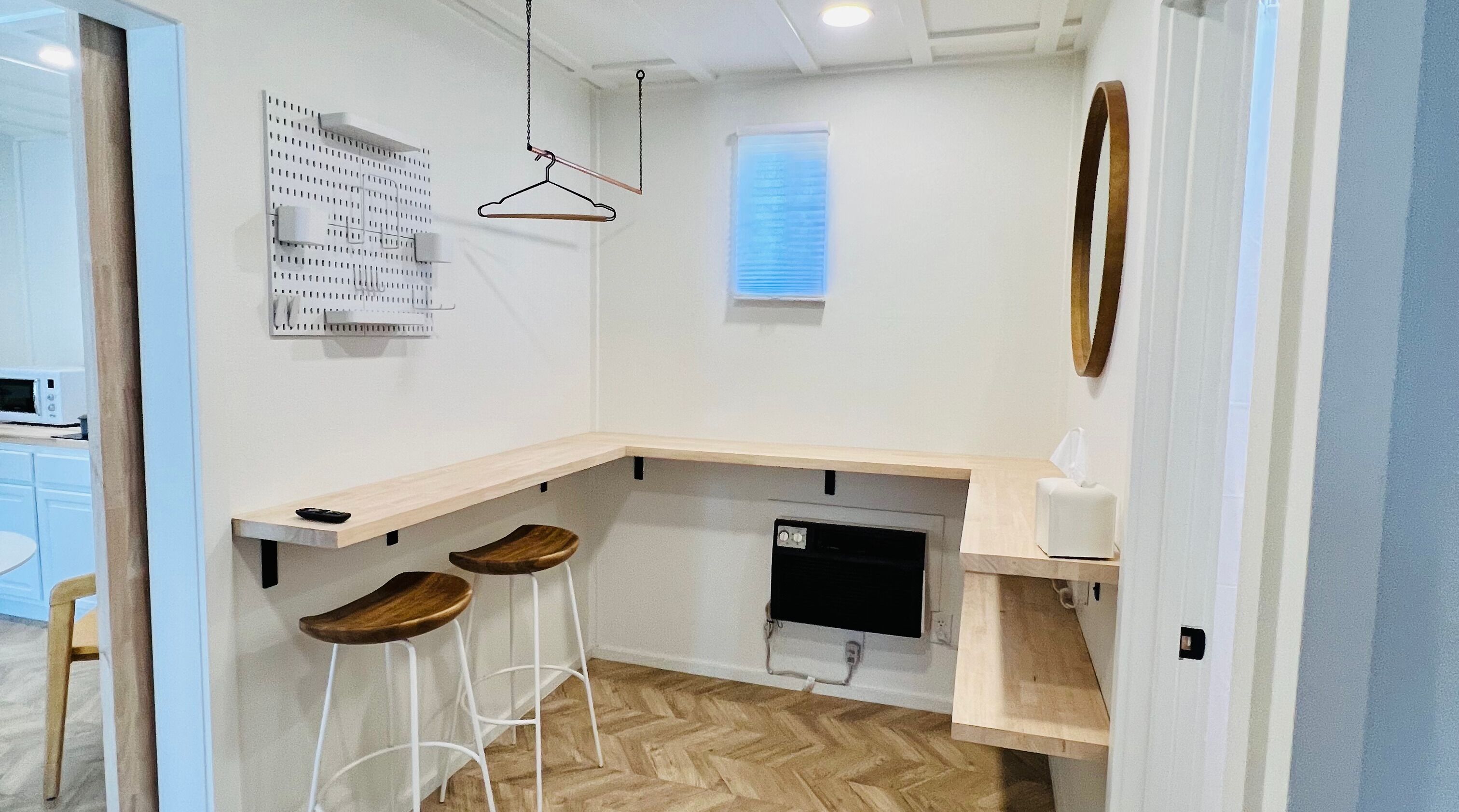 Una cucina compatta con un piano di lavoro in legno, due sgabelli, un forno a microonde e un piccolo frigorifero.