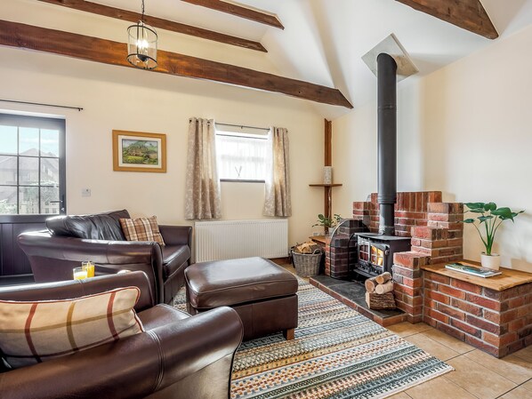 Una sala de estar acogedora con chimenea, sofá de cuero y alfombra estampada.