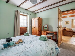 Une chambre à coucher comprenant un lit, une armoire en bois, un bureau et une porte donnant sur une autre pièce.