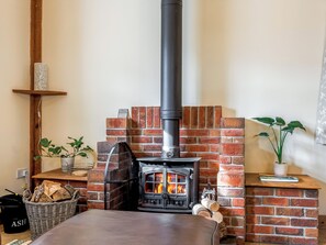 A cozy room with a brick fireplace, a wooden shelf, and a potted plant.