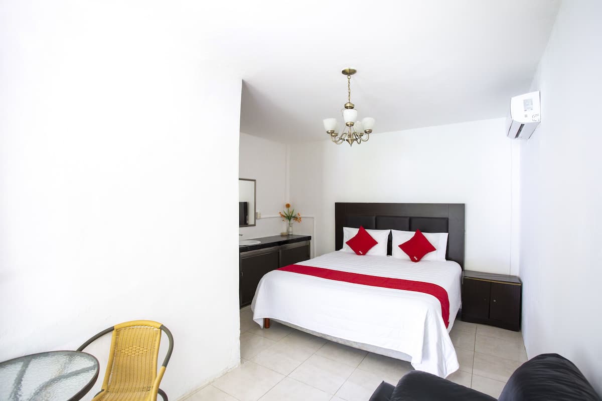 A hotel room with a bed, a nightstand, a chair, and a small table.