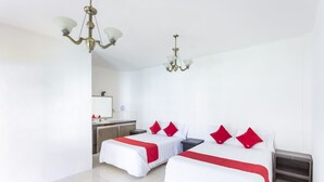 Une chambre d’hôtel avec deux lits, un lustre, un petit bureau et un miroir.
