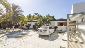 Une voiture blanche est garée dans une allée, avec un bâtiment moderne en arrière-plan.