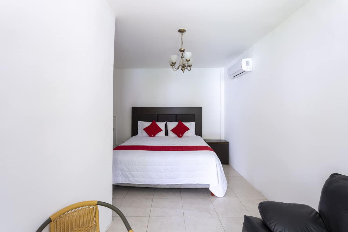 A bedroom with a bed, a chandelier, a nightstand, and a chair.
