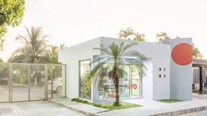 Un bâtiment moderne doté d’une grande façade en verre, de palmiers et d’un design minimaliste.