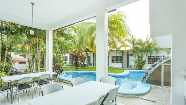 Un espace aménagé au bord de la piscine avec une table et des chaises, une petite piscine et un toboggan.