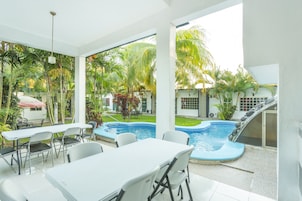 A poolside area with a table and chairs, a small pool, and a slide.