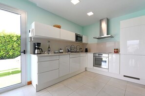 A modern kitchen with white cabinets, a stainless steel oven, and a coffee maker. - Vista Golf 9 (Maspalomas)