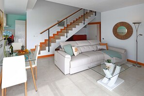 A modern living room with a staircase, a glass coffee table, and a white sofa. - Vista Golf 9 (Maspalomas)