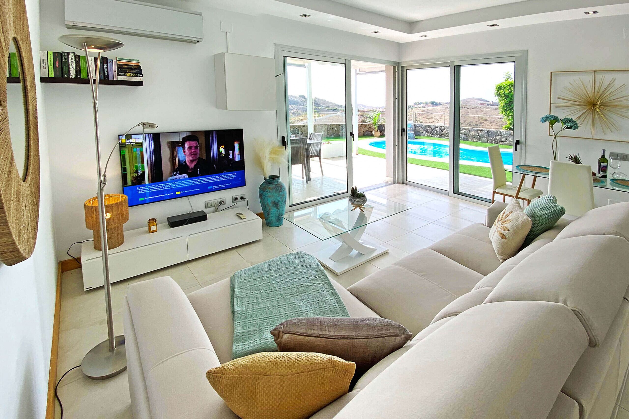 A modern living room with a television, sofa, and a glass table.