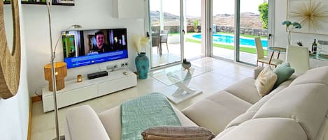 A modern living room with a television, sofa, and a glass table.