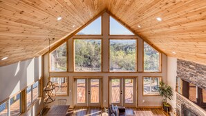 Una habitación amplia con ventanas grandes, techo de madera y chimenea.