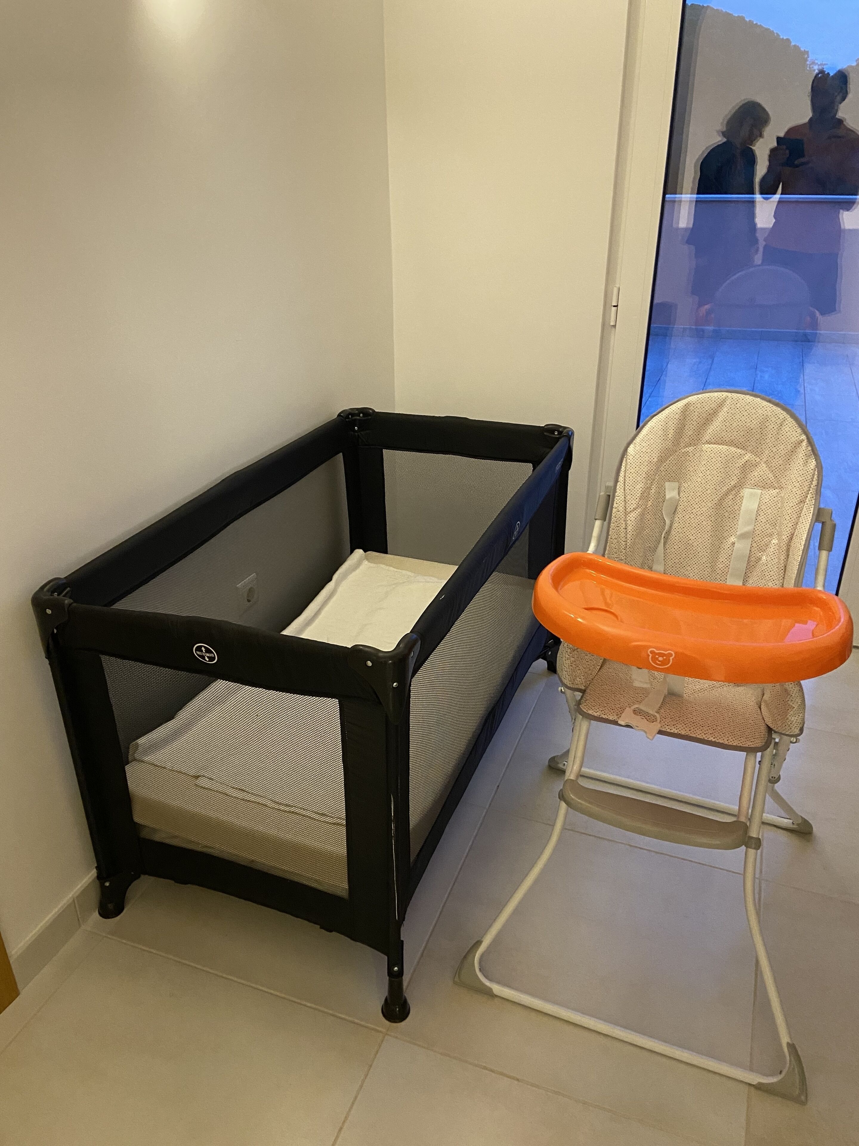 Un cambiador para bebés con una barandilla de seguridad negra y un asiento infantil con un reposabebés naranja.