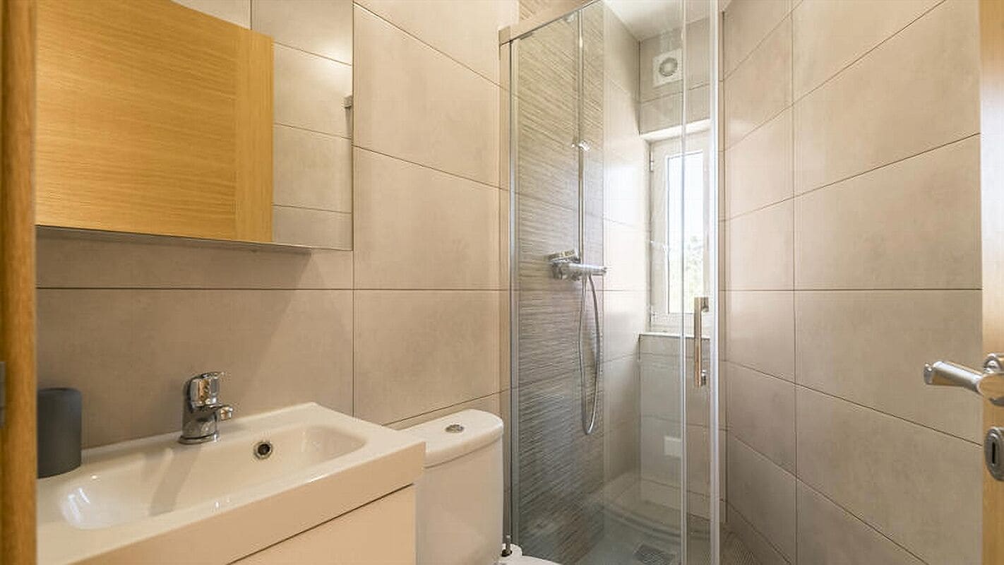 A bathroom with a glass-enclosed shower, a sink, and a toilet.