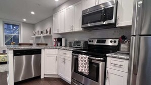 Una cocina moderna con electrodomésticos de acero inoxidable, armarios blancos y un ventanal que proporciona luz natural.