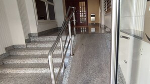 Una escalera con barandillas de metal, un felpudo de corcho al final y una puerta de vidrio que da a una habitación.
