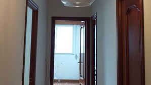 Un pasillo con una lámpara en el techo, puertas de madera y vistas a otra habitación.