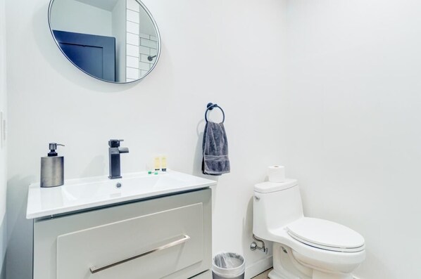 Ein Badezimmer mit einem weißen Waschbecken, einem Spiegel, einem Handtuch und einer Toilette.