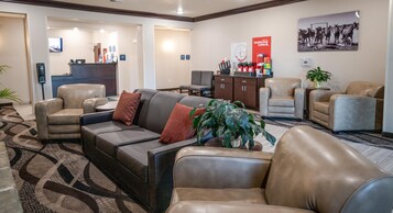 Un vestíbulo de hotel con sofás de cuero, un mostrador de recepción y una zona de café.