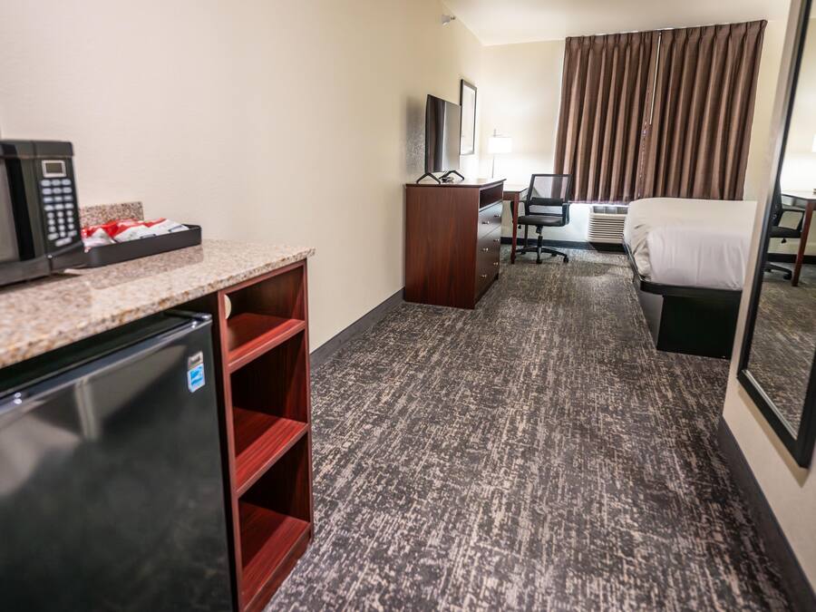 Habitación de hotel con kitchenette, una cama, un escritorio y una silla.
